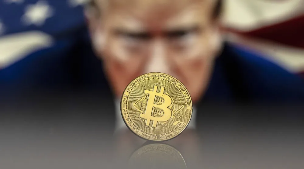 تكوين يظهر عملة تذكارية لعملة «البتكوين» الرقمية أمام صورة للرئيس الأميركي دونالد ترمب (إ.ب.أ)