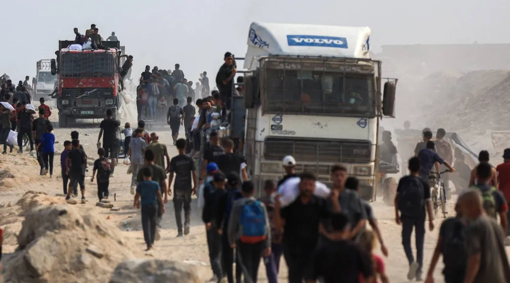 فلسطينيون يسعون للحصول على المساعدات من الشاحنات في بيت لاهيا بشمال قطاع غزة (رويترز)