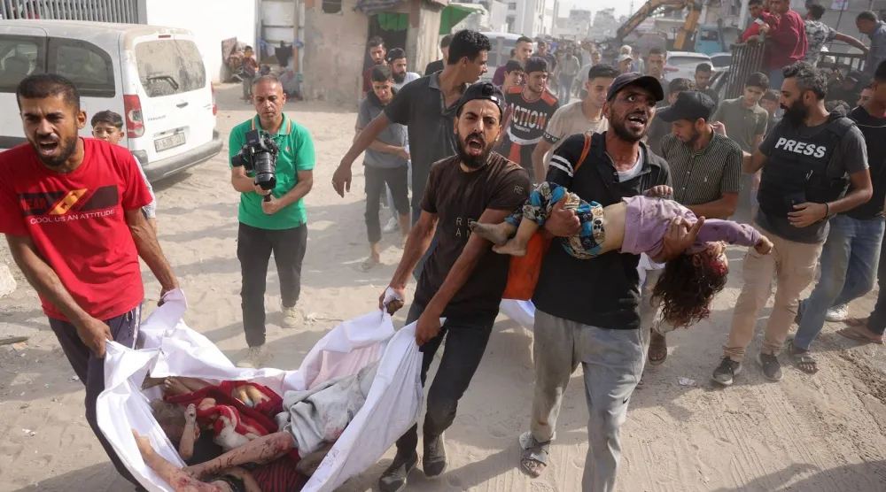 فلسطينيون ينقلون جثث أطفال قُتلوا في غارة إسرائيلية على حي الزيتون إلى مستشفى الشفاء بمدينة غزة (أ.ف.ب)
