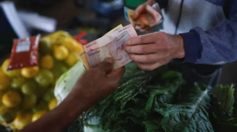رجل يدفع لبائع عند كشك فواكه في مركز توزيع في برازيليا (رويترز)