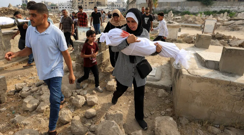 تحمل الفلسطينية سهى طافش جثمان حفيدتها سارة أبو دف التي قُتلت بغارة إسرائيلية في الصباح الباكر على منزلهم وفقاً للمسعفين بمدينة غزة (رويترز)