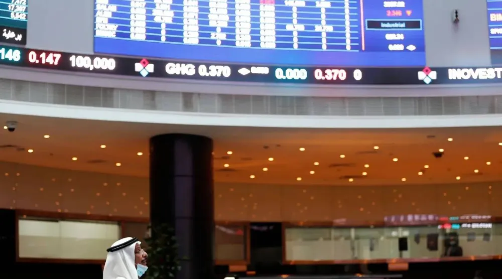 متداول ينظر إلى شاشات تعرض بيانات سوق الأسهم في بورصة البحرين (رويترز)