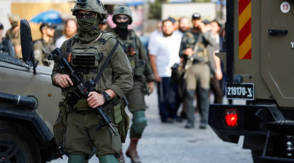 حراسة إسرائيلية أثناء جولة أسبوعية للمستوطنين في الخليل بالضفة الغربية في 9 أغسطس 2025 (رويترز)