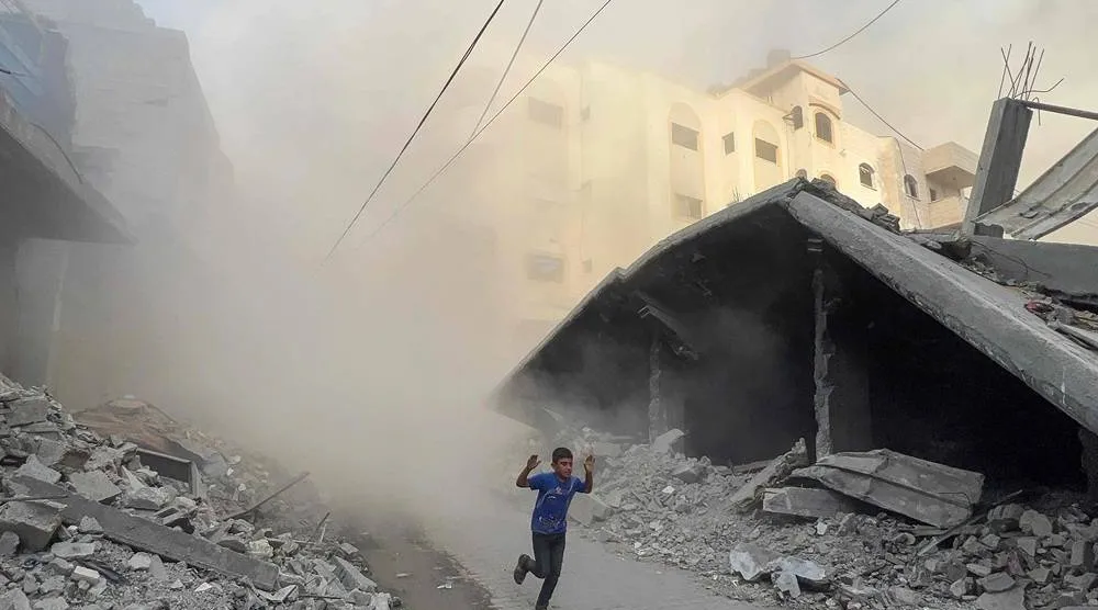 A Palestinian boy rushes away from the site of Israeli air strikes on a six-storey building in the Saftawi neighborhood west of Jabalia in the northern Gaza Strip on August 19, 2025. (AFP) 