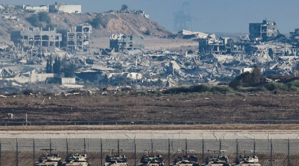 Gazze sınırının İsrail tarafında tanklar, arka planda ise Şeridin büyük çaplı yıkımı görülüyor (Reuters)