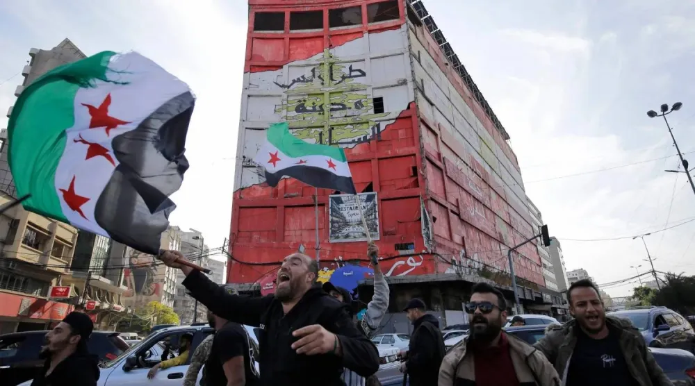 سوريون ولبنانيون يحتفلون بسقوط النظام السوري في مدينة طرابلس شمال لبنان (أرشيفية - أ.ف.ب)