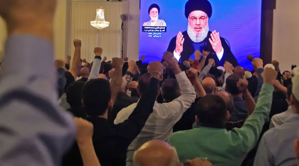 Beyrut'un güney banliyösündeki bir camide dev ekranda Hasan Nasrallah'ın konuşmasını izleyen Hizbullah destekçileri, Kasım 2019 (AFP)