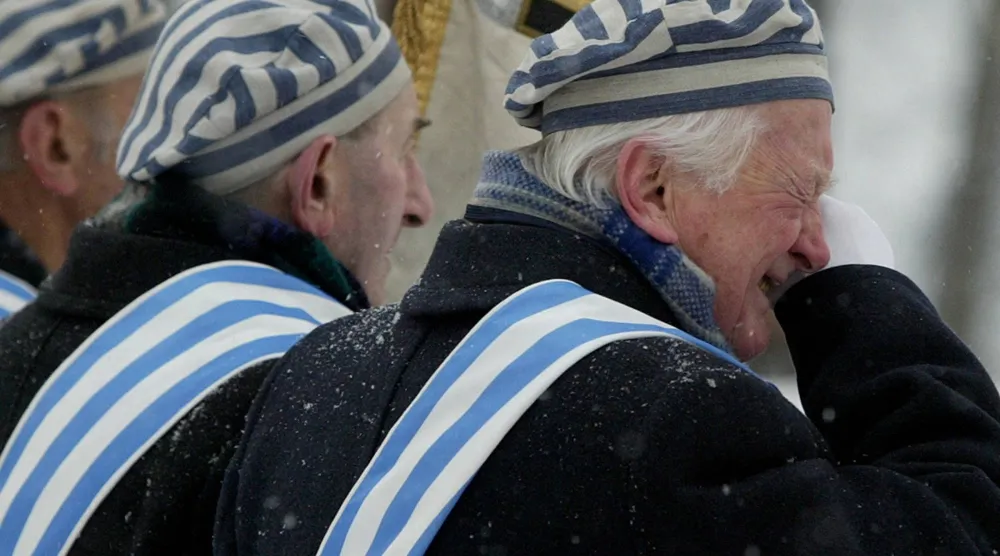 ناجٍ من معسكر اعتقال يمسح دمعة خلال مراسم أقيمت في معسكر الإبادة النازي السابق أوشفيتز بيركيناو ببولندا في 27 يناير 2005 (رويترز)