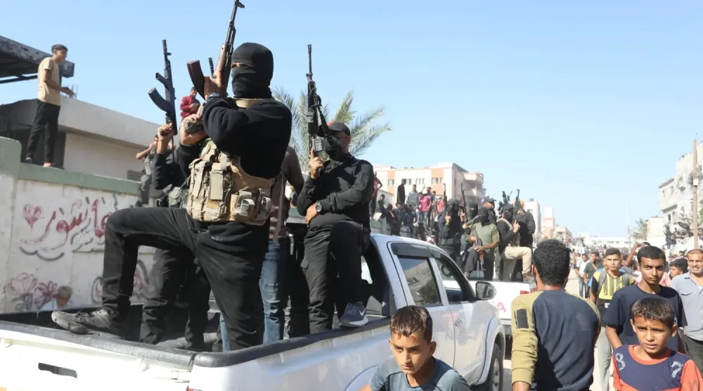 Hamas savaşçıları, 13 Ekim 2025'te Han Yunus'ta İsrail tarafından serbest bırakılan Filistinli mahkûmları taşıyan otobüslere eşlik ediyor. (DPA)