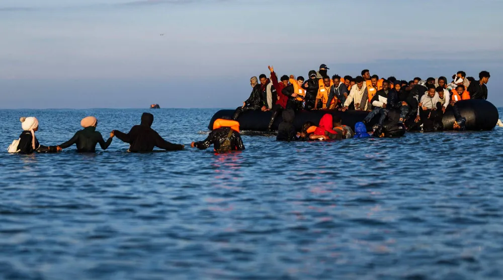 مهاجرون يعبرون البحر للصعود إلى قوارب المهربين ضمن محاولة لعبور القناة الإنجليزية في شمال فرنسا (أ.ف.ب)