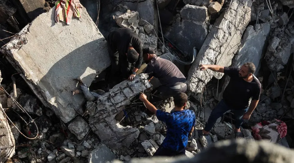 İsrail'in Gazze şehrine düzenlediği saldırı sırasında yıkılan bir evin enkazından ceset çıkaran Filistinliler (AFP)