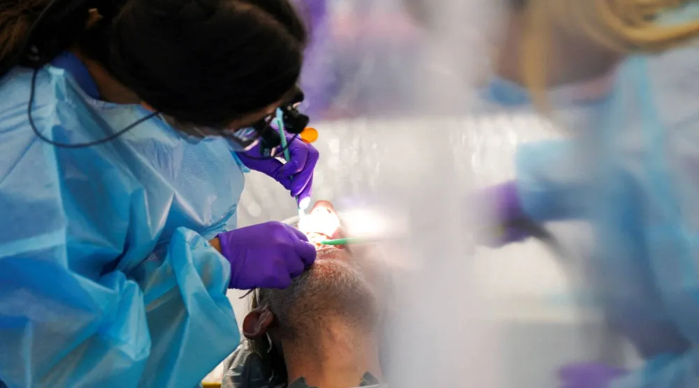 طبيبة أسنان تفحص مريضاً داخل عيادة صحية متنقلة في تينيسي بالولايات المتحدة (رويترز)