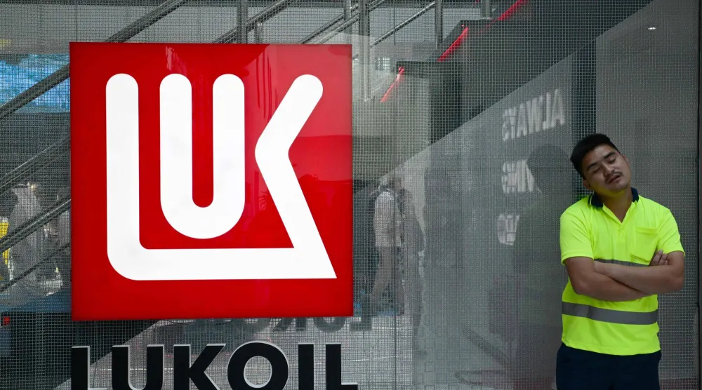 رجل يقف بجانب شعار شركة النفط الروسية العملاقة «لوك أويل» في معرض ومؤتمر أبوظبي الدولي للبترول (أ.ف.ب)