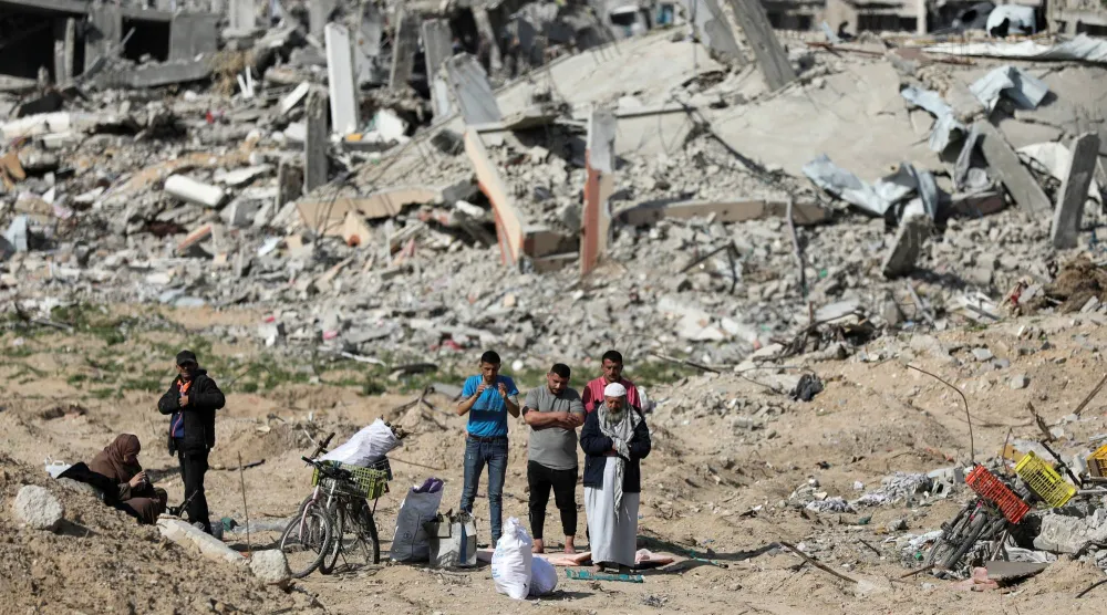 فلسطينيون يصلون أمام الأنقاض بعد عودتهم إلى حيّهم المدمر بعد وقف إطلاق النار بين إسرائيل و«حماس» (رويترز)