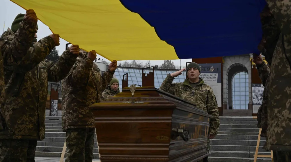 جنود من حرس الشرف يحملون العلم الأوكراني فوق نعش جندي أوكراني (أ.ف.ب)