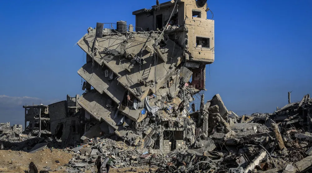 فلسطينيون يقفون أمام مبنى مدمر في خان يونس (د.ب.أ)