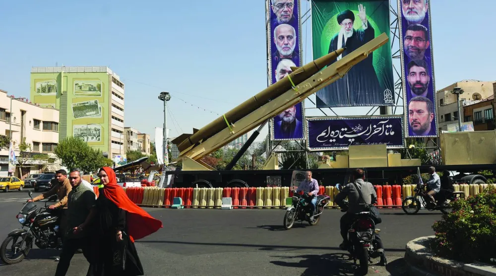 صاروخ إيراني يعرض بجانب لافتة تحمل صورة المرشد علي خامنئي وقادة من «الحرس الثوري» بأحد شوارع طهران قُتلوا في هجمات إسرائيلية (رويترز)