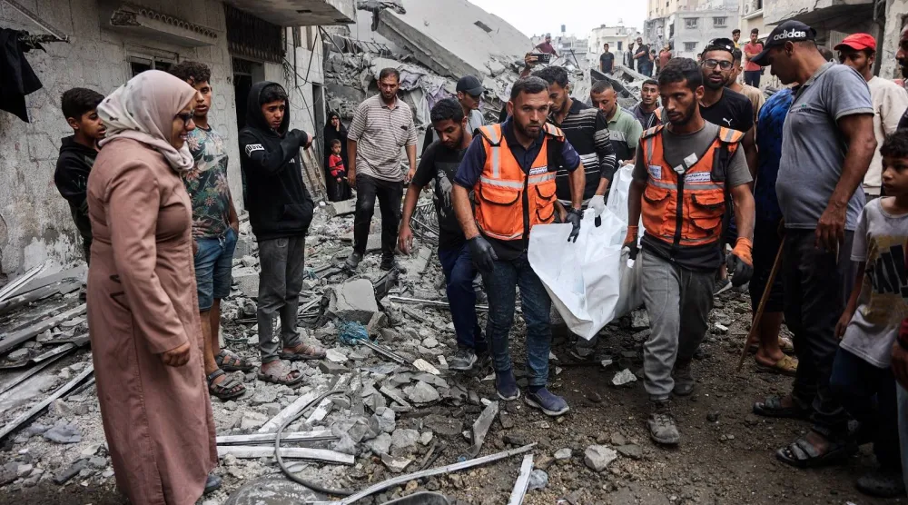 فلسطينيون يحملون جثثاً انتشلوها من بين أنقاض منزل دمر في غارة إسرائيلية بمدينة غزة (أ.ف.ب)