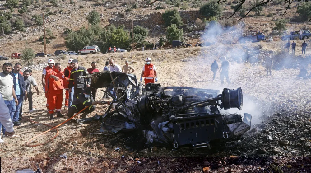 مواطنون وعناصر من الصليب الأحمر اللبناني يتفقدون حطام سيارة استهدفتها طائرة مُسيّرة إسرائيلية في بلدة شبعا جنوب لبنان أمس (إ.ب.أ)
