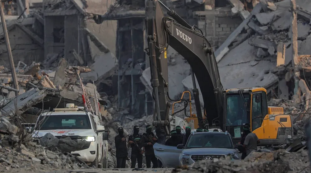 مقاتلو «كتائب القسام» إلى جانب عمال الصليب الأحمر خلال البحث عن جثث رهائن إسرائيليين في مدينة غزة (إ.ب.أ)