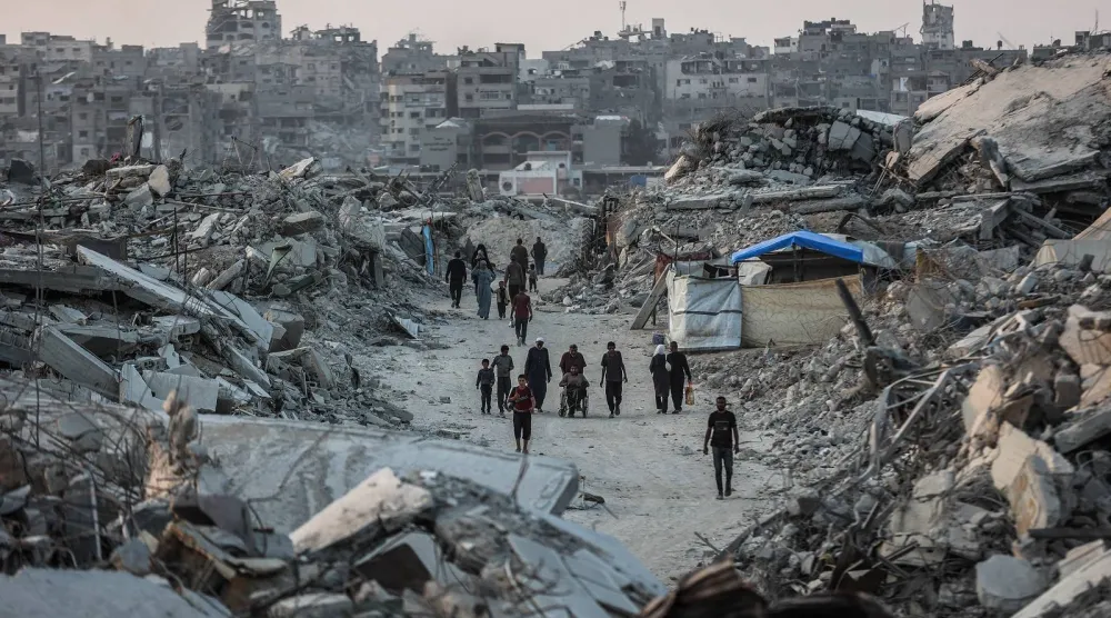 فلسطينيون يسيرون وسط أنقاض المباني المدمرة في جباليا شمال قطاع غزة (أ.ف.ب)