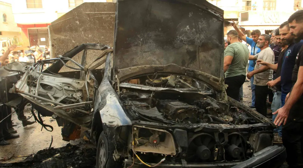 مواطنون يتفقدون حطام مركبة استهدفتها طائرة مسيَّرة إسرائيلية ببلدة الدوير في جنوب لبنان (أ.ف.ب)