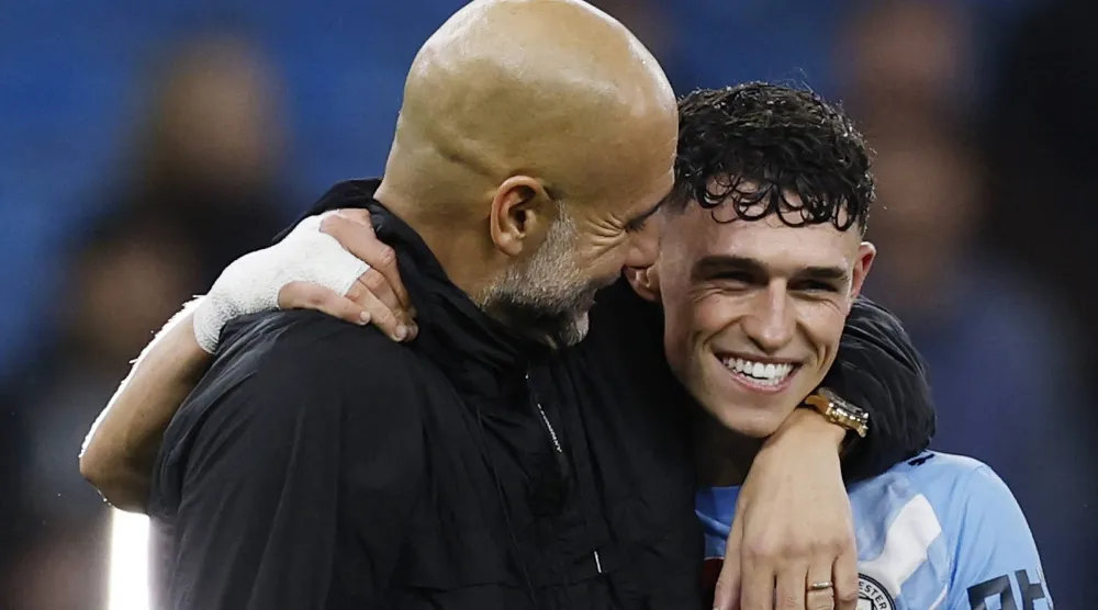 الإسباني بيب غوارديولا يحتفل بالفوز مع لاعبه فيل فودن (رويترز)