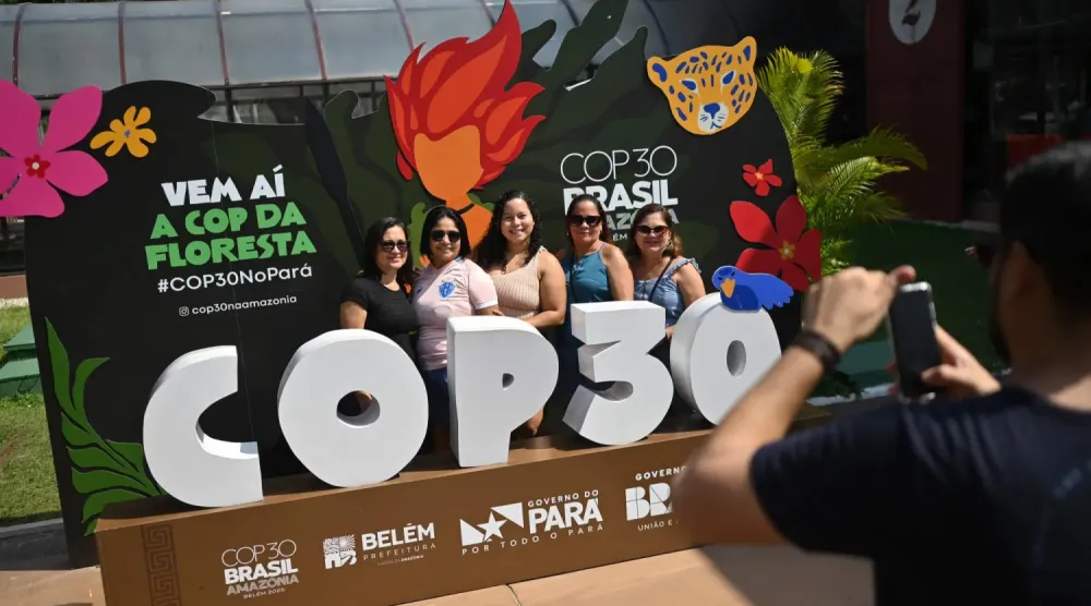 Belem'deki Estaçao das Docas turistik limanında Birleşmiş Milletler İklim Değişikliği Konferansı'nın afişiyle fotoğraf çektiren kadınlar (AFP)