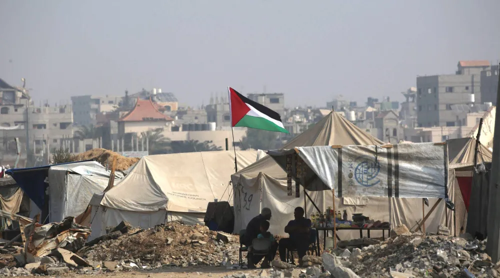 Palestinians sit outside their make shift homes along a road near the Nuseirat refugee camp in the central Gaza Strip, on November 9, 2025, following a US-brokered truce that halted the two-year war. (AFP)