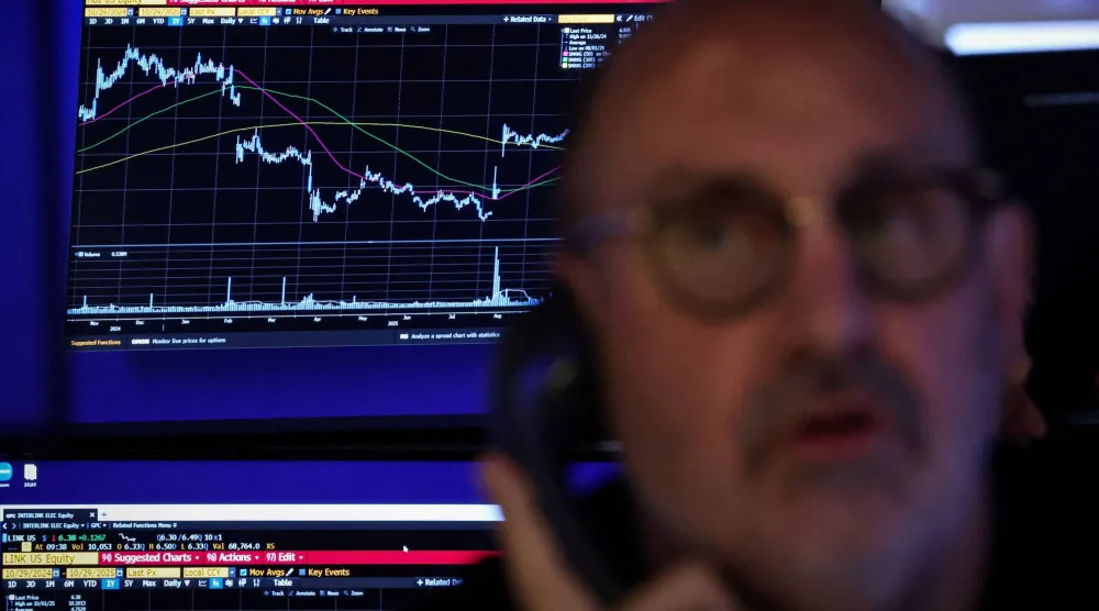 متداول يعمل في «وول ستريت» وخلفه شاشة تعرض مؤشرات الأسهم (رويترز)