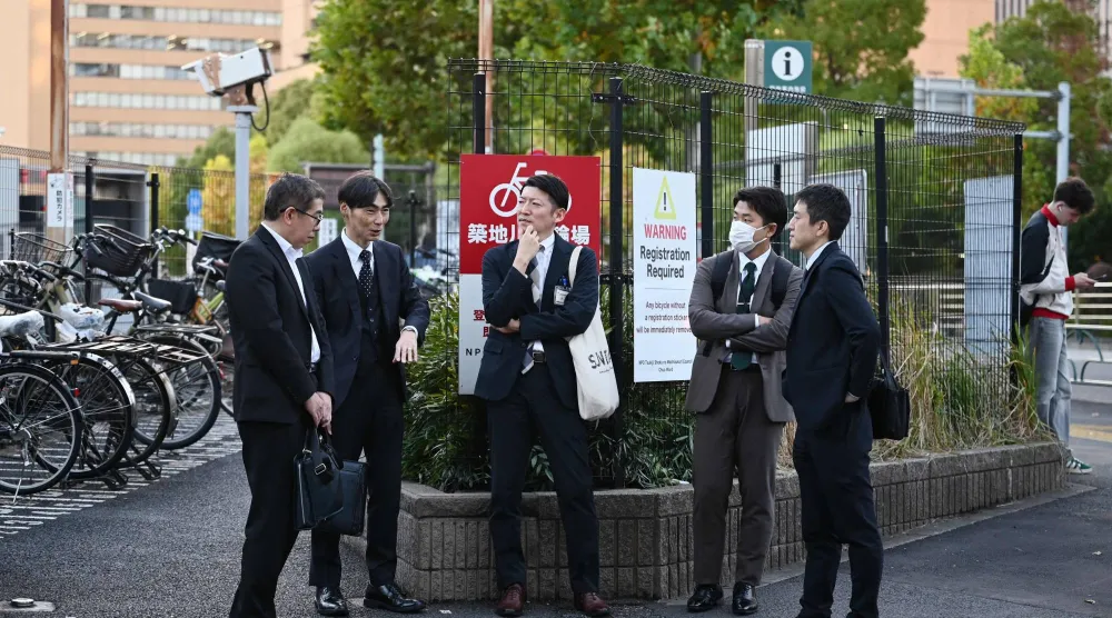 موظفون يتحدثون في أحد شوارع الضاحية المالية بالعاصمة اليابانية طوكيو (أ.ف.ب)