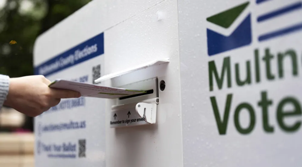 ناخب يُسقط بطاقة اقتراع بالبريد في أحد الصناديق أثناء التصويت في الانتخابات التمهيدية للرئاسة الأميركية (أرشيفية - أ.ب)