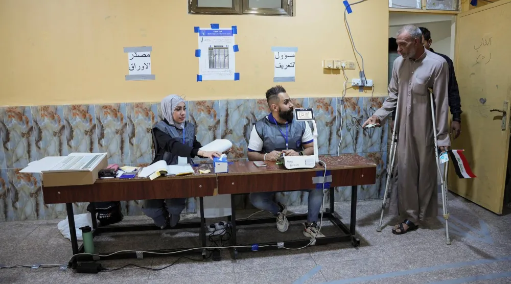 أشخاص يدخلون إلى مركز اقتراع في البصرة للإدلاء بأصواتهم (رويترز)