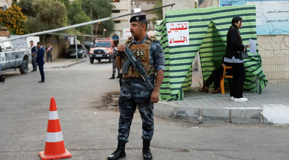 فرد أمن خارج مركز اقتراع بالعراق (رويترز)