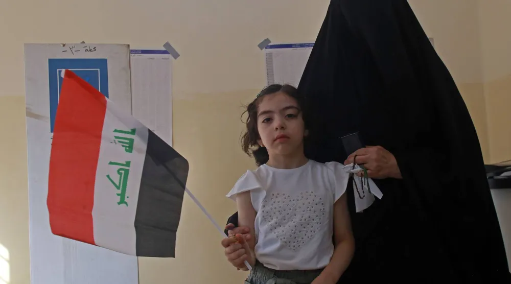 سيدة عراقية مع ابنتها داخل أحد مراكز الاقتراع في الانتخابات البرلمانية اليوم (إ.ب.أ)