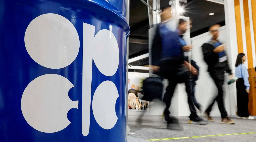 أشخاص يمرون أمام تركيب فني يصور برميل نفط يحمل شعار «أوبك» في باكو (أرشيفية - رويترز)