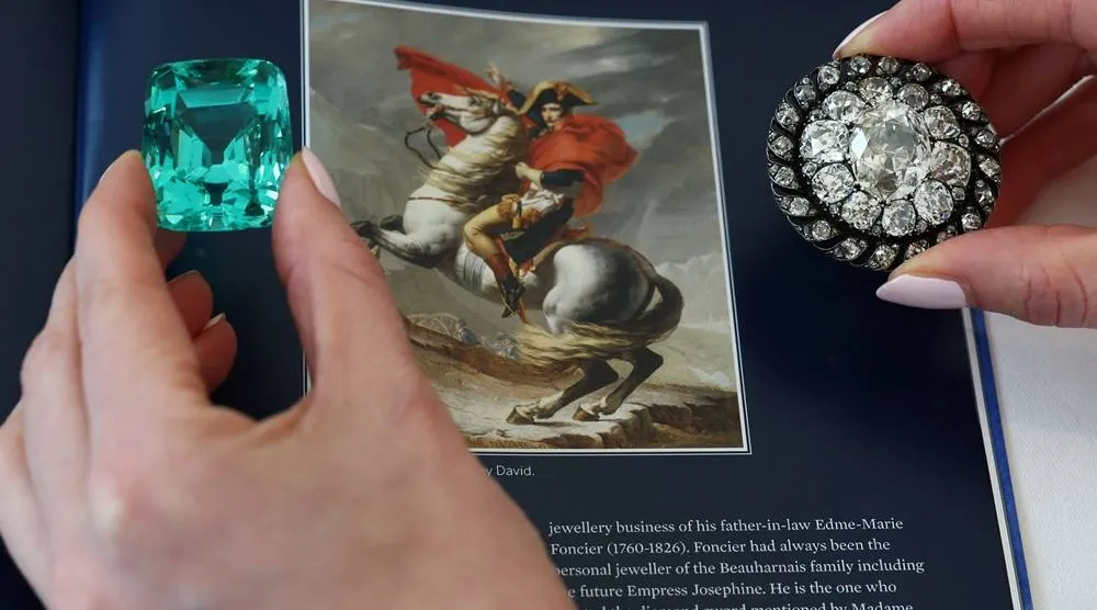  A staff member holds a 132.66 carats green beryl worn by Emperor Napoleon I at his coronation and an old mine-cut diamond brooch or pendant owned by Emperor Napoleon I during an auction preview for Sotheby’s in Geneva, Switzerland, November 6, 2025. (Reuters)