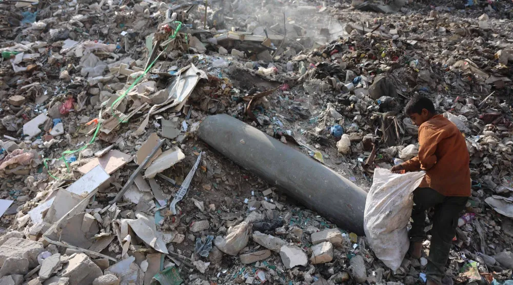 طفل فلسطيني يجمع البلاستيك بالقرب من صاروخ لم ينفجر في مكب نفايات بمدينة غزة أمس (أ.ف.ب)