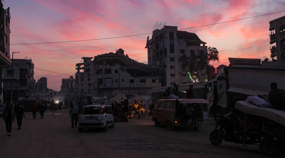 فلسطينيون يسيرون بالقرب من مبانٍ مدمرة في مدينة غزة وسط وقف إطلاق نار بين إسرائيل و«حماس» (إ.ب.أ)
