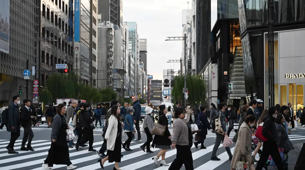 مشاة يعبرون الطريق في ضاحية غينزا التجارية وسط العاصمة اليابانية طوكيو (أ.ف.ب)