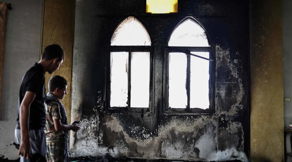 فلسطينيون يعاينون الأضرار التي ألحقها مستوطنون الخميس بمسجد الحاجة حميدة في قرية دير استيا الفلسطينية قرب سلفيت بالضفة الغربية المحتلة (أ.ف.ب)