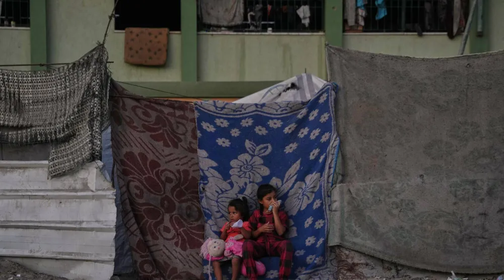 فتاتان فلسطينيتان تجلسان أمام الخيمة التي تسكنها عائلتهما في خان يونس جنوب قطاع غزة (أ.ب)