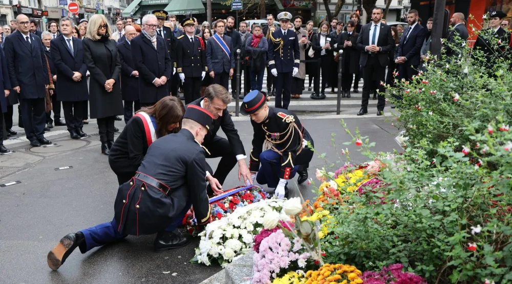 الرئيس إيمانويل ماكرون ورئيسة بلدية باريس آن هيدالغو يضعان إكليلاً من الزهور قريباً من مقهى «بون بيير» الذي استهدفه الإرهابيون ليلة 13 نوفمبر 2015 (إ.ب.أ)