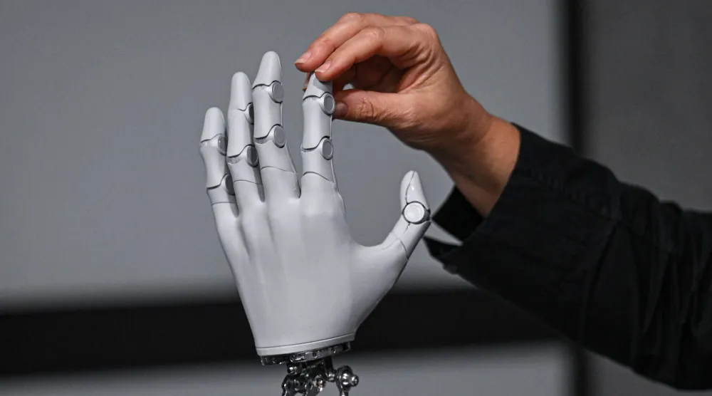 صحافي يلمس يد روبوتية على شكل إنسان من الجيل التالي من شركة «إكس بينغ» في مقرها الرئيسي في قوانغتشو (أ.ف.ب)