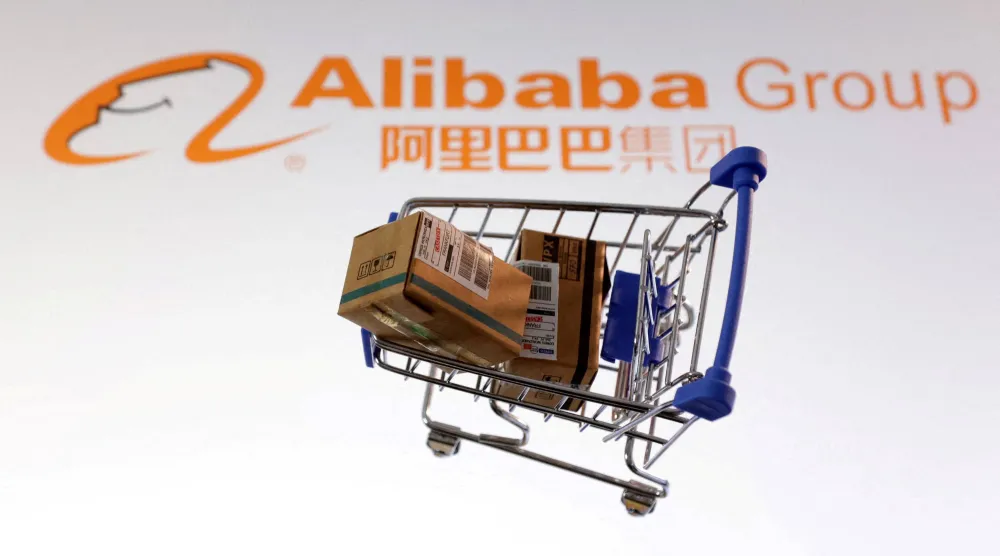 عربة تسوق وفي الخلفية شعار مجموعة «علي بابا» الصينية (رويترز)