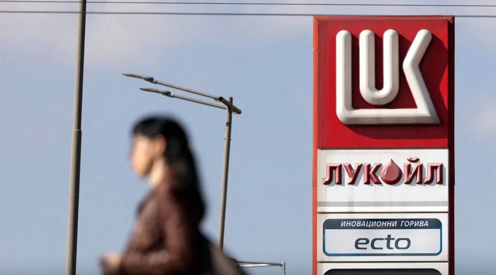 امرأة تمشي بالقرب من محطة وقود تابعة لشركة «لوك أويل» في صوفيا (رويترز)