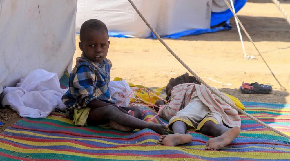 El Faşir'li çocuklar, kuzeydeki ed-Dabba kasabasındaki yerinden edilmiş Sudanlılar için kurulan kampta çadırlarının dışında dinleniyor (AFP)