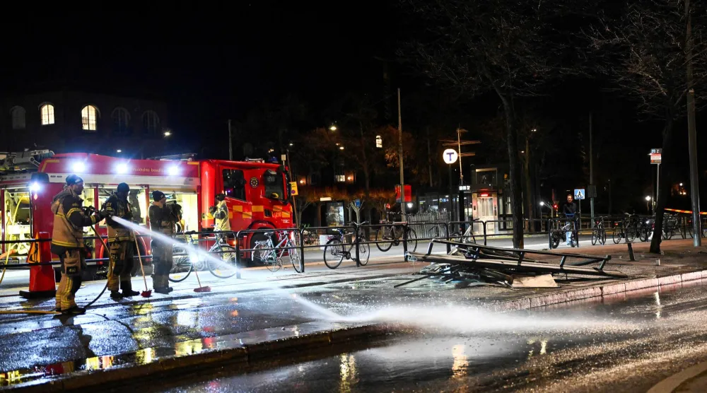 رجال إطفاء يرشون الماء بموقع حادثة اصطدام حافلة بمحطة انتظار بأوسترمالم في استوكهولم (رويترز)