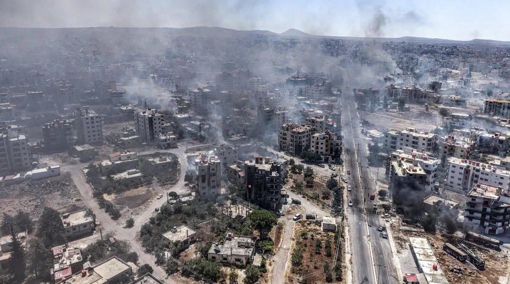 صورة جوية تُظهر الدخان يتصاعد من مدينة السويداء وسط اشتباكات سابقة (د.ب.أ)