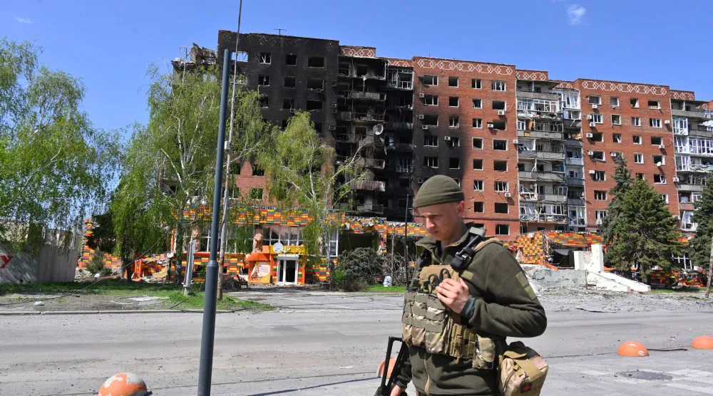 جندي أوكراني يسير بجوار مبانٍ متضررة وسط بوكروفسك في منطقة دونيتسك بأوكرانيا (أ.ب)